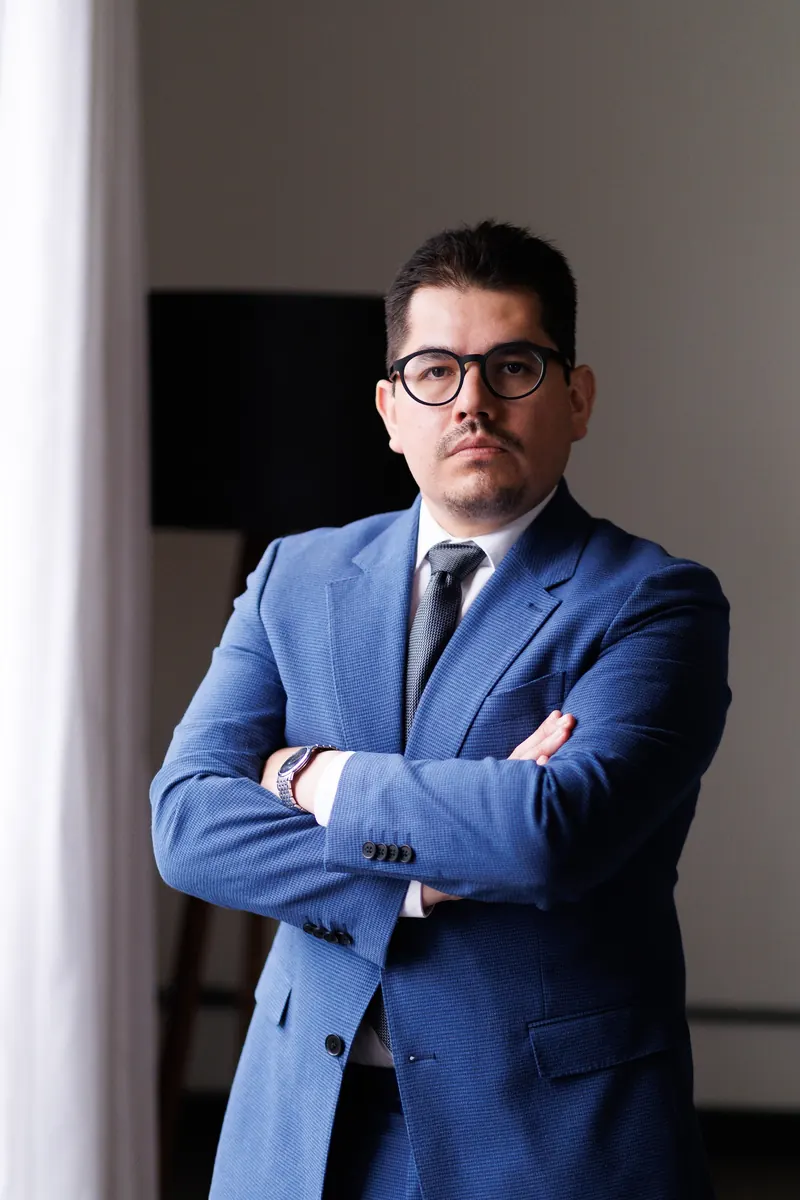 Dr. John Terrazas de terno azul, com os braços cruzados