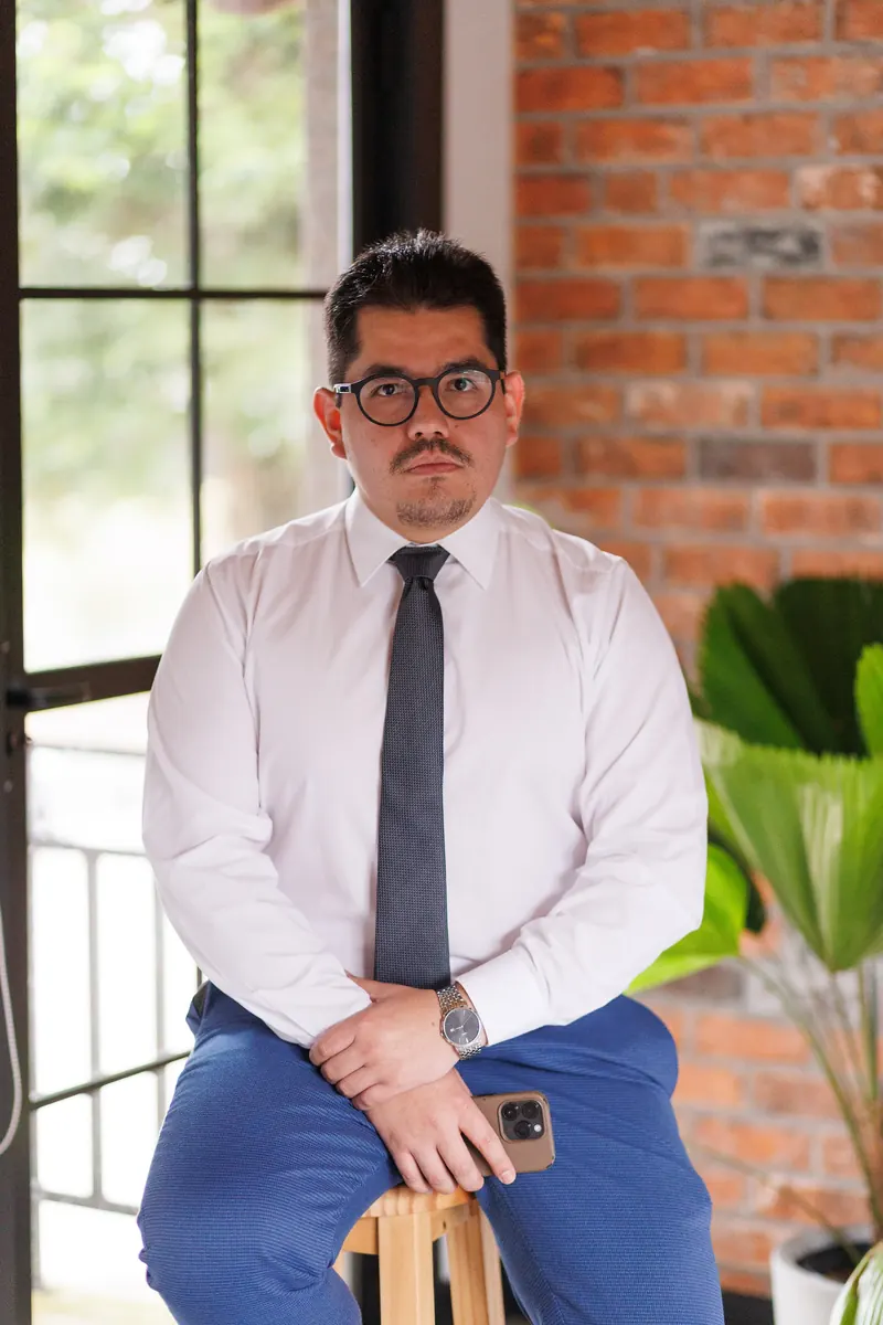 Dr. John Terrazas sentado junto a uma janela, de camisa branca