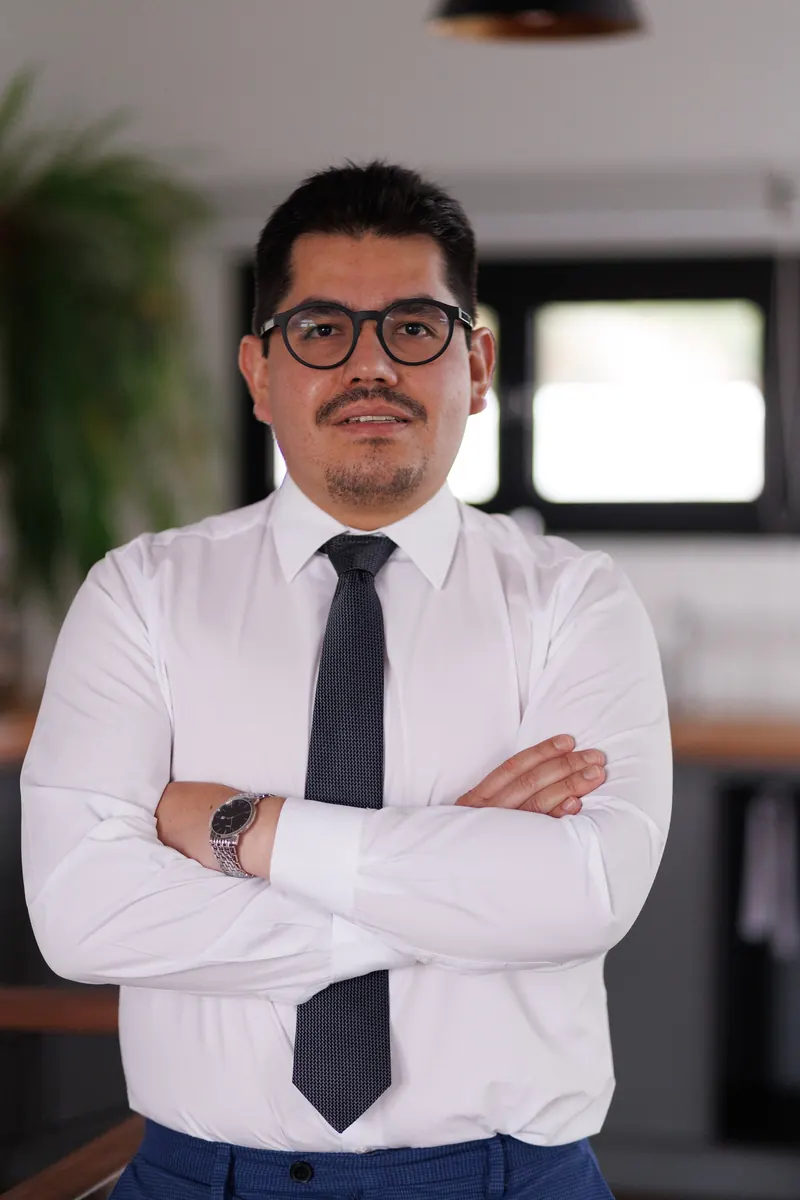 Dr. John Terrazas de camisa branca e gravata, com os braços cruzados