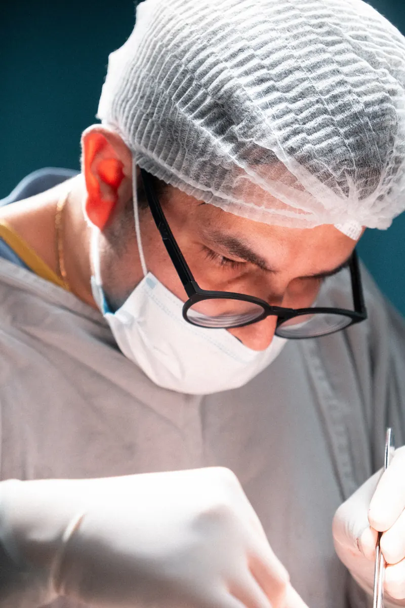 Dr. John Terrazas operando, em detalhe, de touca e máscara