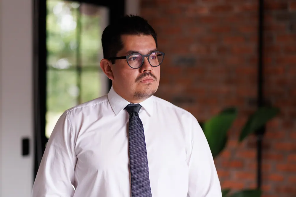 Dr. John Terrazas olhando pela janela, de camisa branca